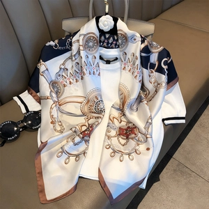 Elegant 90cm silk scarf with chain pattern draped on a white knit top and leather handbag