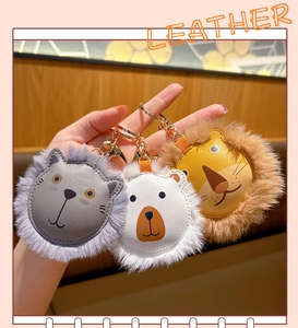 Detailed view of leather animal keychains with fluffy fur trim and gold metal rings