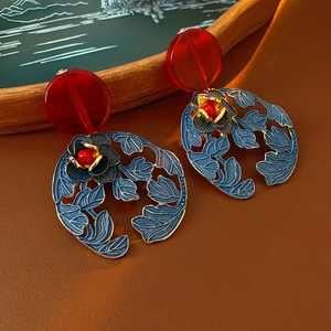 Macro view of vintage style hollow flower earrings with red resin and blue petals