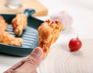 Close-up of realistic faux fried chicken wing with golden crispy texture and oily shine