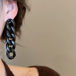Close-up of matte black acrylic chain drop earrings worn with a minimalist style