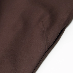 Close-up of deep brown fabric texture and precise stitching on the mock neck dress