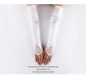 Detail of white bridal satin gloves with floral lace embroidery and fingerless design