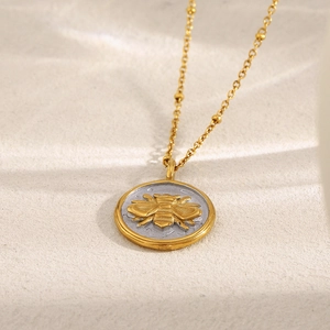Détail macro du collier à perles plaqué or 18 carats avec pendentif pièce abeille bicolore
