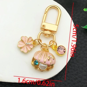 Détail du porte-clés doré en forme de U avec breloques fleur et coquillage roses