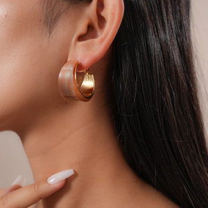 Close-up of elegant C-shaped amber resin hoop earrings worn by a female model