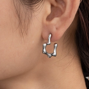 Sleek silver irregular geometric stainless steel earring worn by a model in close-up shot