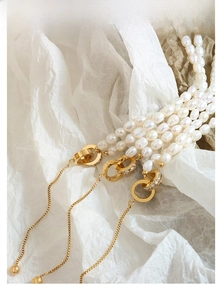 Detailed macro of baroque freshwater pearl necklace with Roman numeral gold pendant