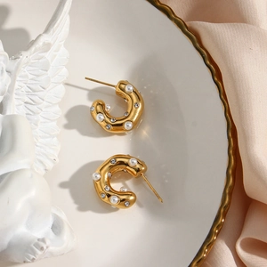 Pendientes en C bañados en oro de 18K con perlas y circón en un plato de cerámica