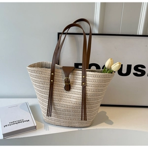 Detailed texture of straw woven tote with brown leather straps and buckle decor