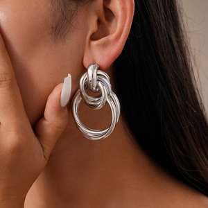 Detail of silver metallic interlocking hoop knot earrings worn by a model in studio light