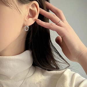 Minimalist silver irregular round stud earrings and matching ring on a female model