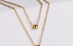 Detail of gold titanium steel double necklace with round bead and rectangle pendant