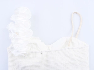 Détail du haut en maille blanche avec volants floraux 3D asymétriques et bride tressée