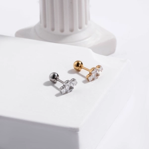 Detailed view of gold and silver steel cartilage studs with three square zircon stones