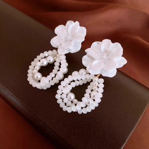 Détail de boucles d'oreilles fleurs blanches avec perles sur un support en cuir marron