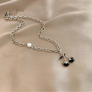 Detail of silver chain necklace with black cherry pendant and single white pearl accent