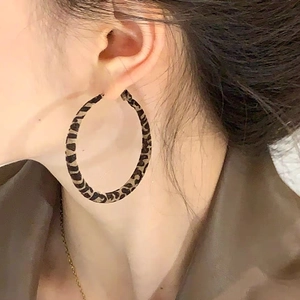 Boucles d'oreilles créoles léopard tendance au design géométrique portées par un mannequin