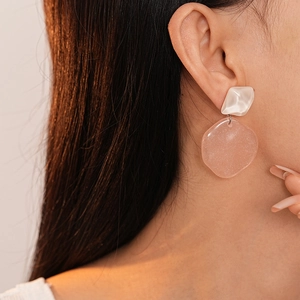 Detail of model wearing pink and white resin geometric earrings with a shimmering texture