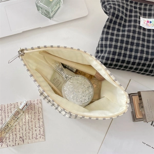 Dettaglio di pochette trucco a quadretti che mostra lo spazio interno e la zip
