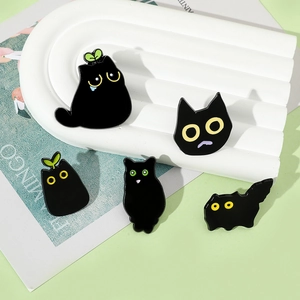 Detailed close-up of five cute black cat enamel pins in various playful poses