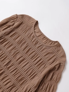 Detailed macro view of the pleated fabric texture and neckline on this brown long sleeve top