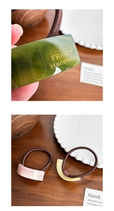Detailed close-up of acetate hair ties with gold emblem on a natural wooden table