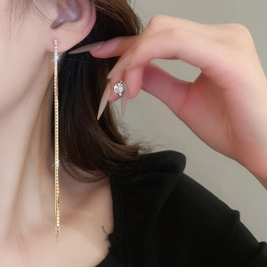Close-up of long tassel rhinestone earrings in gold finish worn by a model