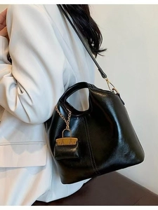 Classic black oil wax leather tote bag with gold chain and mini pouch charm on a model