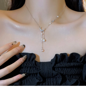 Macro view of moon pendant with diamond inlay and elegant long pearl tassel details