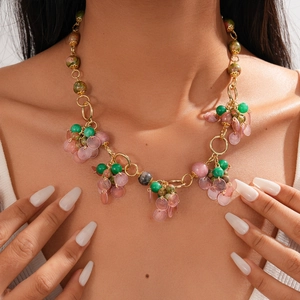 Detail of beaded ethnic necklace featuring green stones, pink beads and gold rings