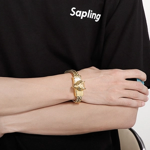 Detail of gold wolf head punk bracelet with double wheat chain on male model wrist
