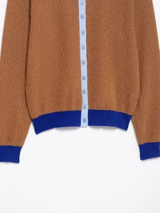 Makroaufnahme der Strickjacke mit Kontrastfarben, blauen Knöpfen und Rippbündchen