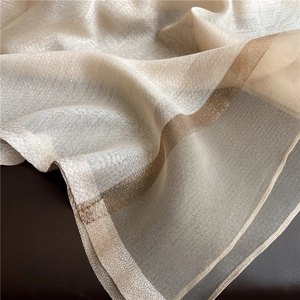 Detalle macro de tela de organza beige transparente con elegante borde de rayas doradas