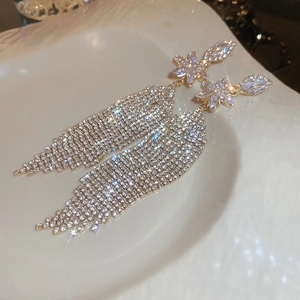 Close-up of sparkling floral stud earrings with long tassel chains and micro-pave zircons