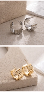 Detailed view of C-shaped metal earrings with striped texture in gold and silver finish