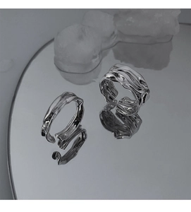 Detail of silver irregular geometric open rings with liquid metal texture on mirror