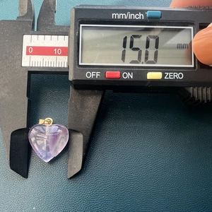 Macro view of purple heart stone pendant measured with caliper showing 15.0 mm size