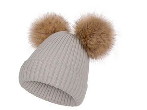 Détail de la maille côtelée et des pompons marron doux sur un bonnet tricoté gris clair