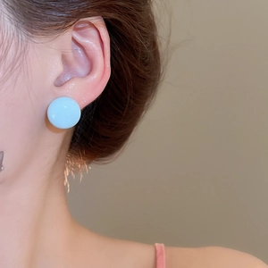 Close-up of a model wearing a light blue round porcelain stud earring on earlobe