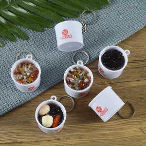 Miniature artificial porridge bowl keychains with realistic grains on a blue knit background