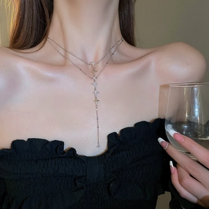 Detail of silver double-layered Y-shaped necklace with star pendant on female model