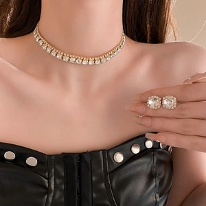 Close-up of elegant gold choker necklace and square stud earrings set with clear crystals