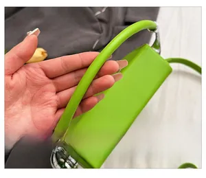 Close-up of bright green leather bag with round handle and silver metal hardware