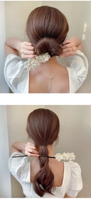 Detail of elegant hair bun maker featuring three organza flowers with pearl centers