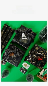 Close-up of black and gold Christmas wrapping paper with snowflake and tree patterns