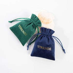 Detail of dark green and navy velvet drawstring jewelry pouches with gold stamping