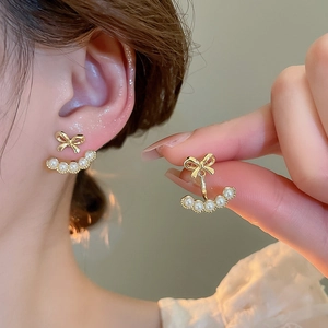 Detail of 18k gold plated bow earrings with dangling white pearls and elegant layered design