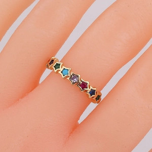 Macro detail of gold knuckle ring featuring multi-colored star-shaped gemstones