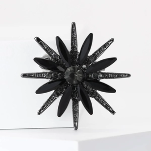 Macro shot of black starburst brooch with dark crystals and sparkling metal details